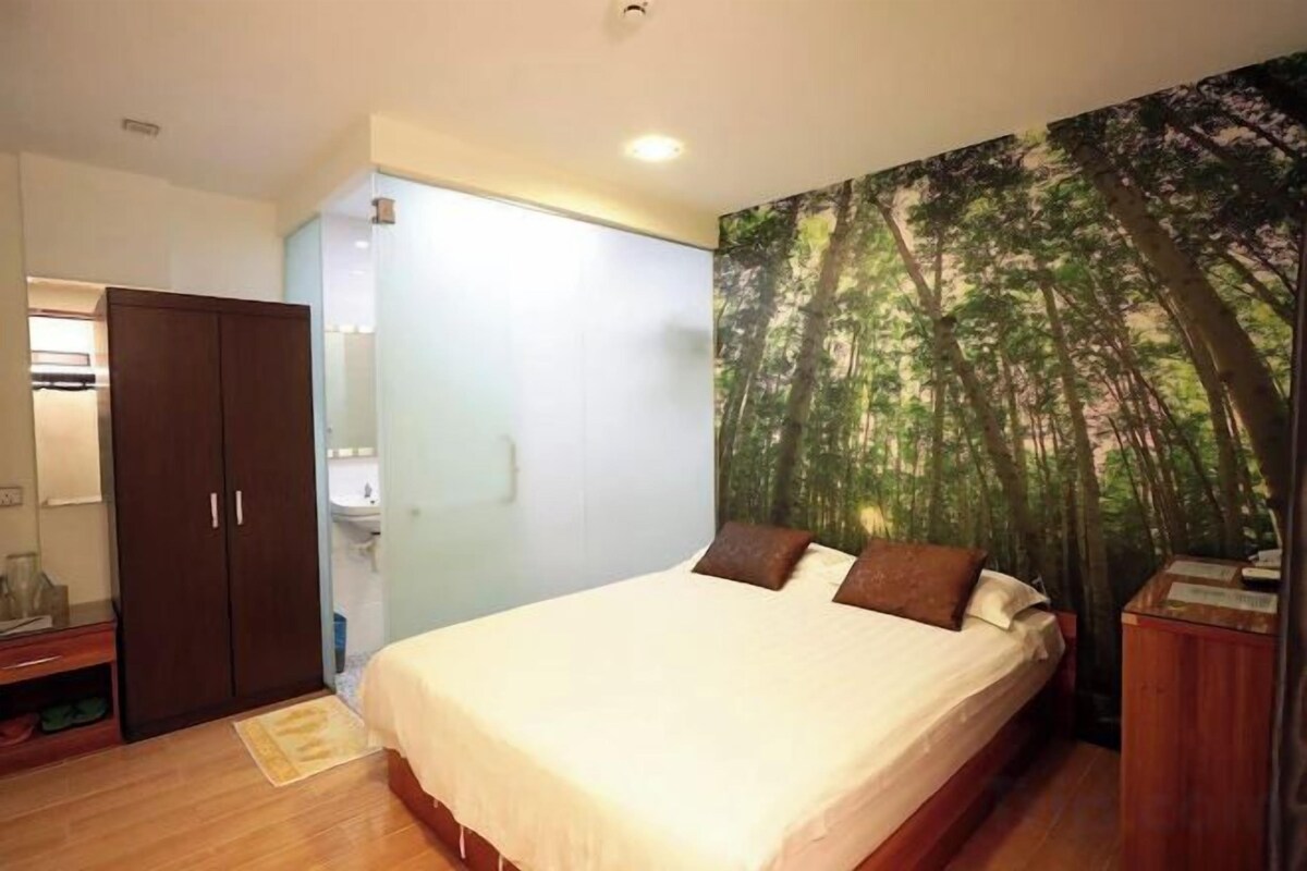 A bedroom with a bed, a wardrobe, and a bathroom visible in the background.