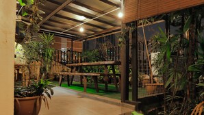 An indoor atrium with a wooden staircase, potted plants, and a green artificial grass area. - Rain Forest Hotel (Kuala Lumpur)