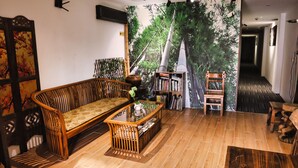 A traditional-style living room with a sofa, a coffee table, and a bookshelf. - Rain Forest Hotel (Kuala Lumpur)