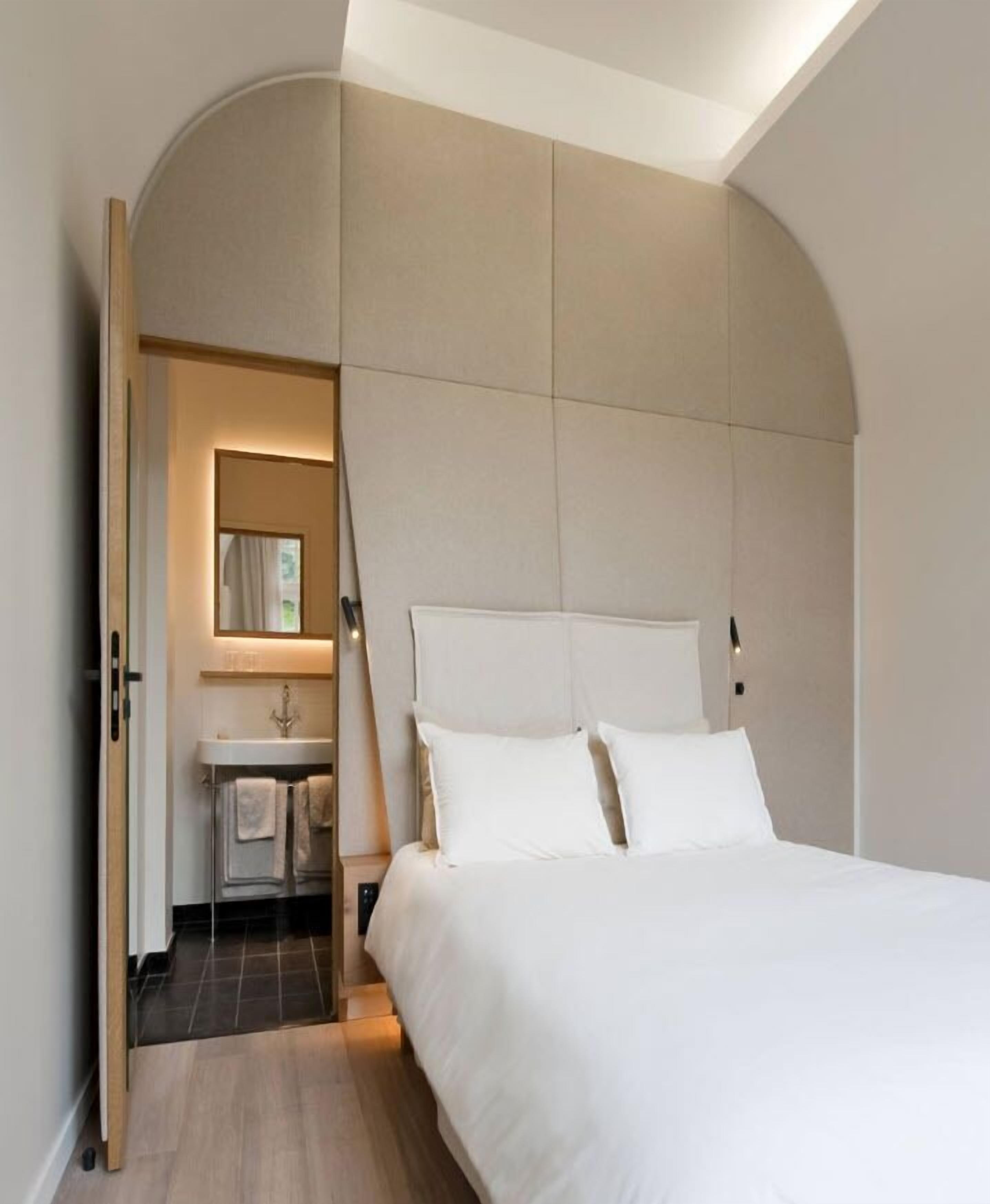 A modern bedroom with a large bed, a built-in vanity, and a curved ceiling.