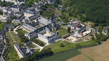 Ein Luftbild eines historischen Schlosskomplexes mit mehreren Gebäuden, Innenhöfen und umliegenden grünen Feldern.