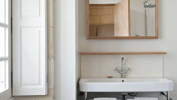 Un bagno con un lavandino bianco, uno specchio e una doccia.