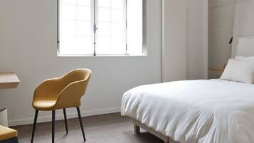 Un dormitorio con cama, escritorio, silla y ventana.