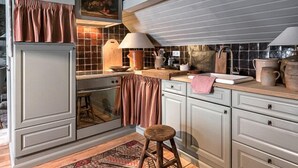 Eine Küche mit hoher Decke, Holzschränken, einem gemusterten Teppich und einem Hocker.