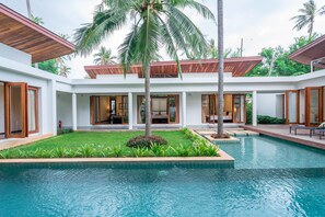 Un moderno resort con piscina, palmeras y un césped cuidado.