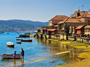 A coastal town with stone buildings, a clear blue sea, and boats.