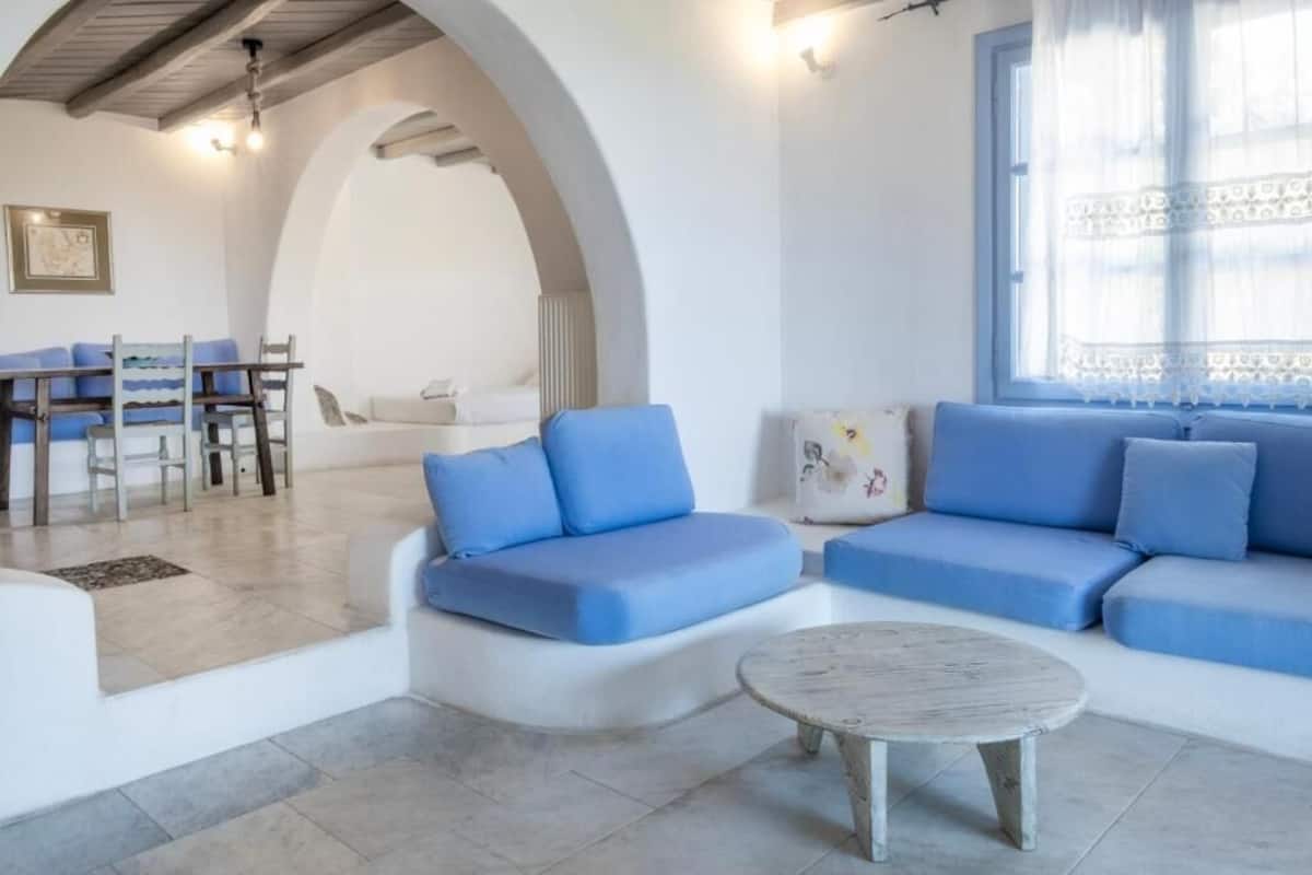 Una sala de estar moderna con un conjunto de sofás, una mesa redonda de centro y un comedor con sillas y una mesa.