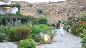 A stone pathway leading to a white building with a garden. - Nama Villas (Mykonos)