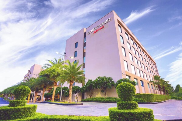 A Courtyard Marriott hotel with a modern design, featuring a central courtyard with palm trees and well-maintained landscaping. - Courtyard by Marriott Agra (Agra)