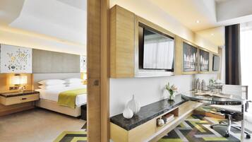 A modern hotel room with a bed, bedside table, lamp, and a large mirror.
