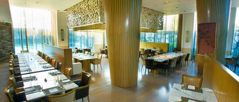 Un vaste espace dédié à la salle à manger, avec de grandes tables et des chaises hautes, de larges fenêtres et des colonnes décoratives.