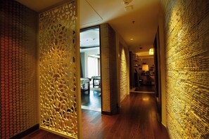A hallway with wooden flooring, decorative panels, and a brick wall.