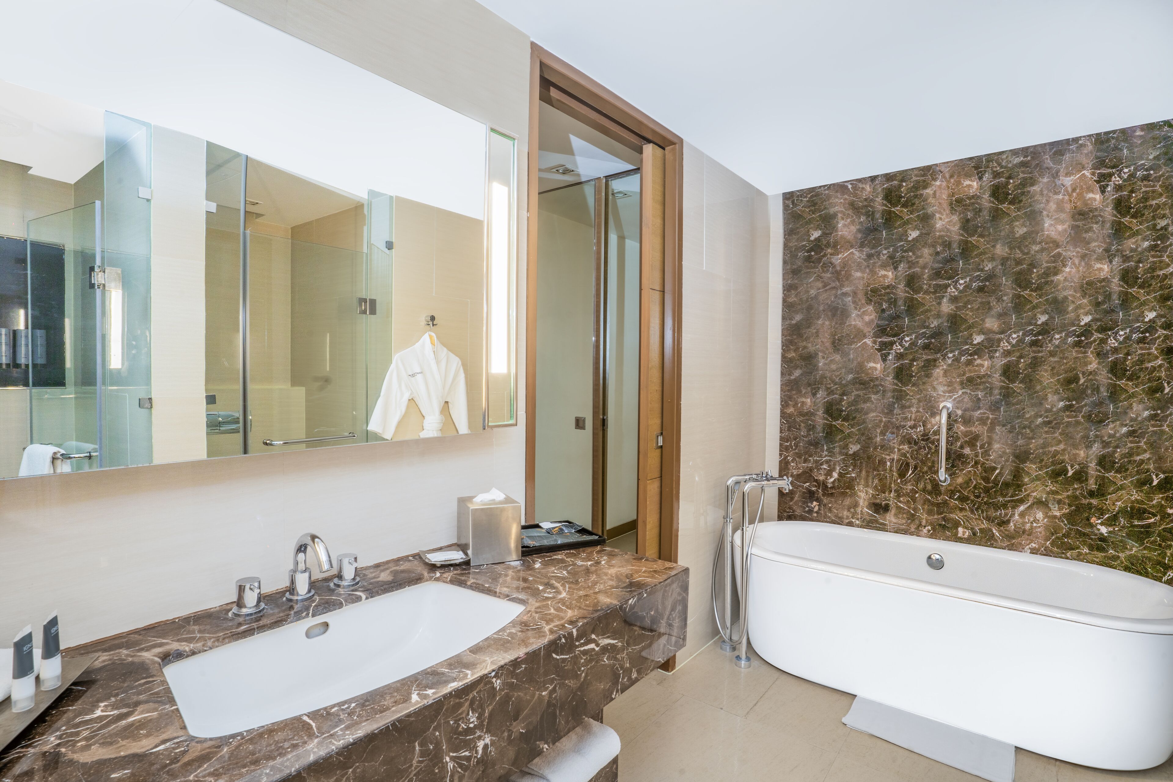 A modern bathroom with a marble vanity, a large mirror, a bathtub, and a glass shower enclosure.