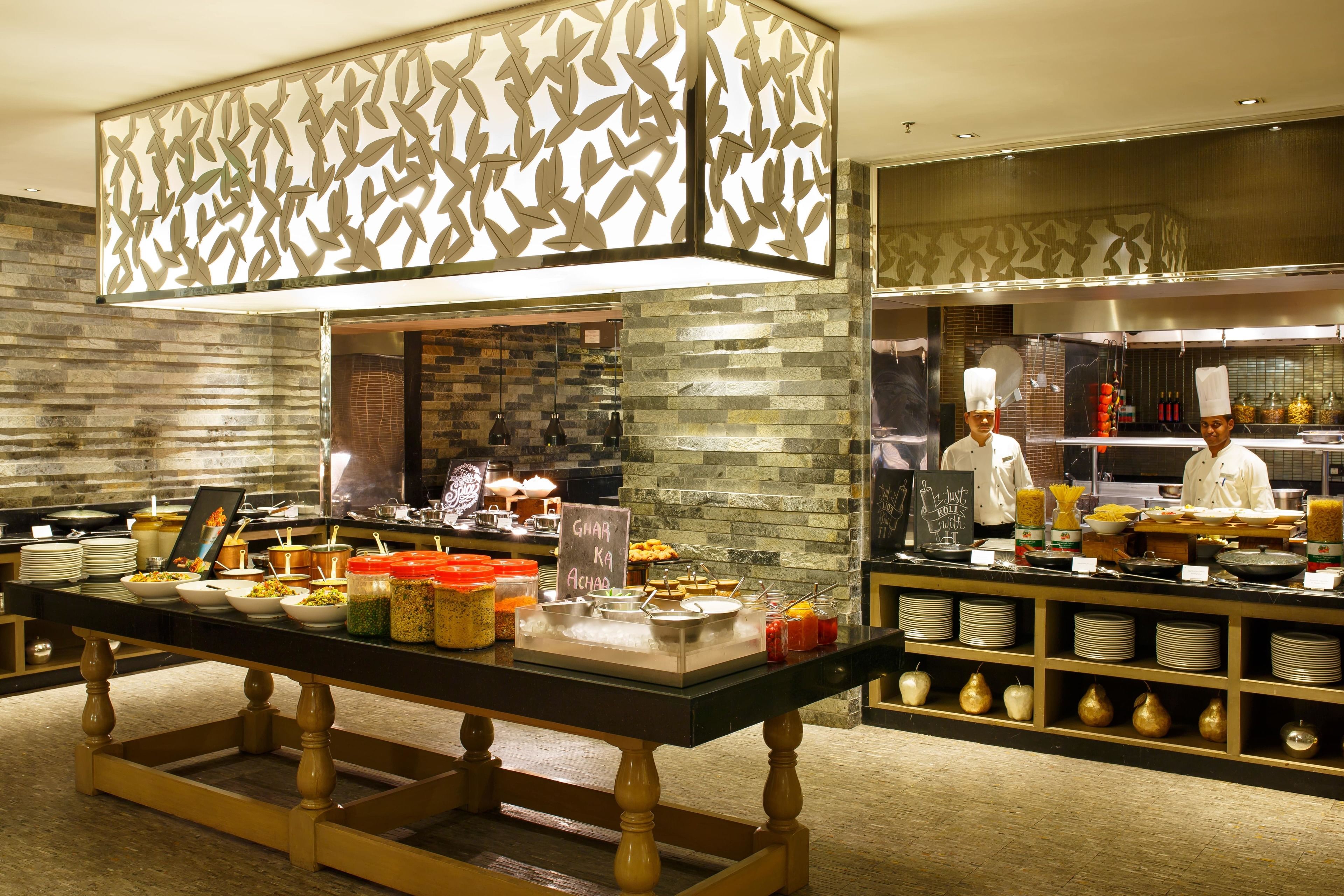A buffet setup with various food items and a chef preparing food in the background.