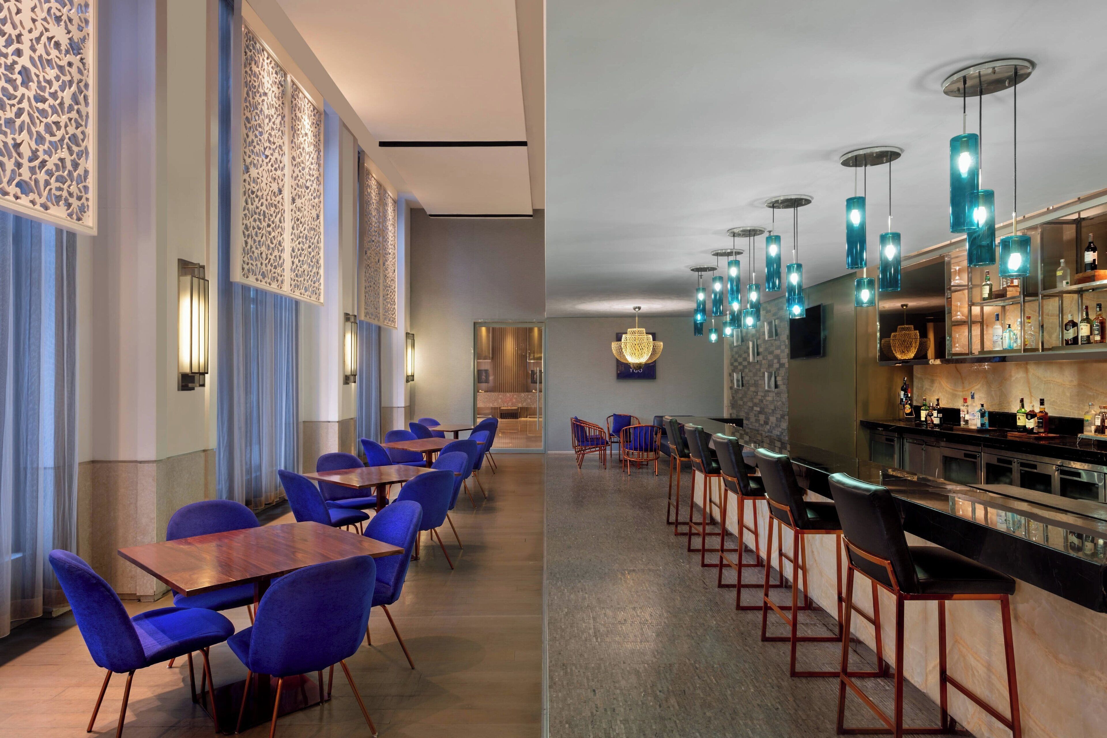 A modern bar area with blue chairs and a long counter.