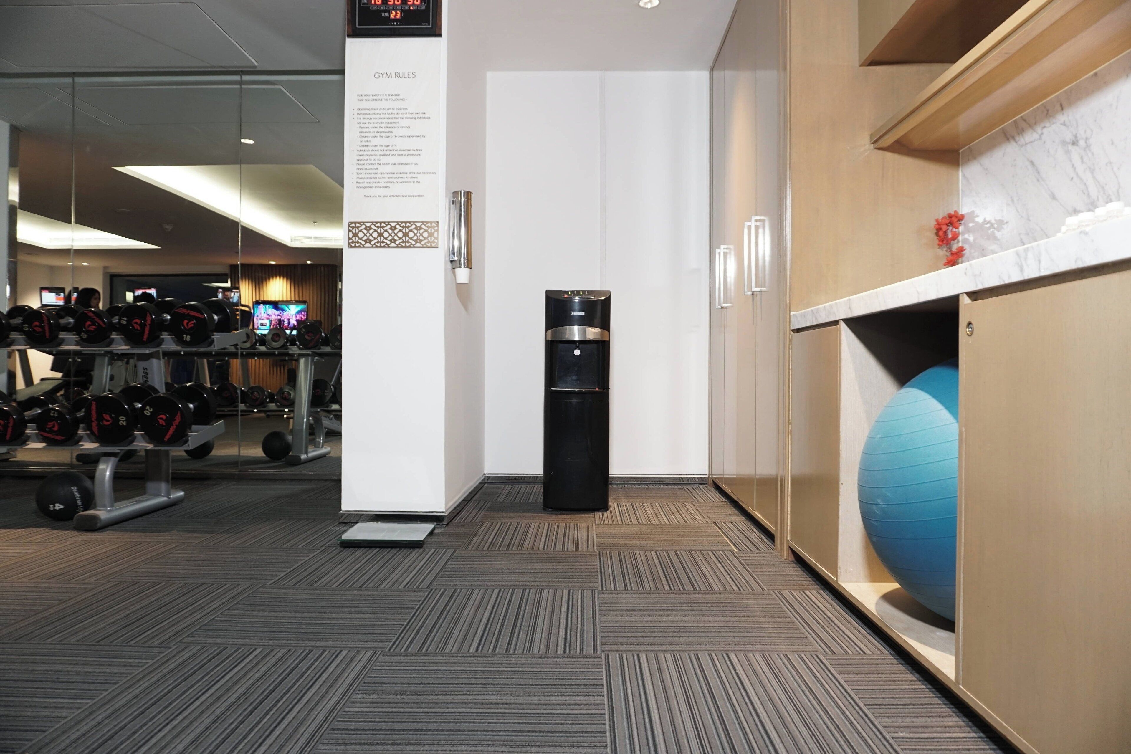 A gym area with exercise equipment, a water dispenser, and a blue exercise ball.