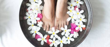 A bowl with white and pink flowers and a pair of feet.