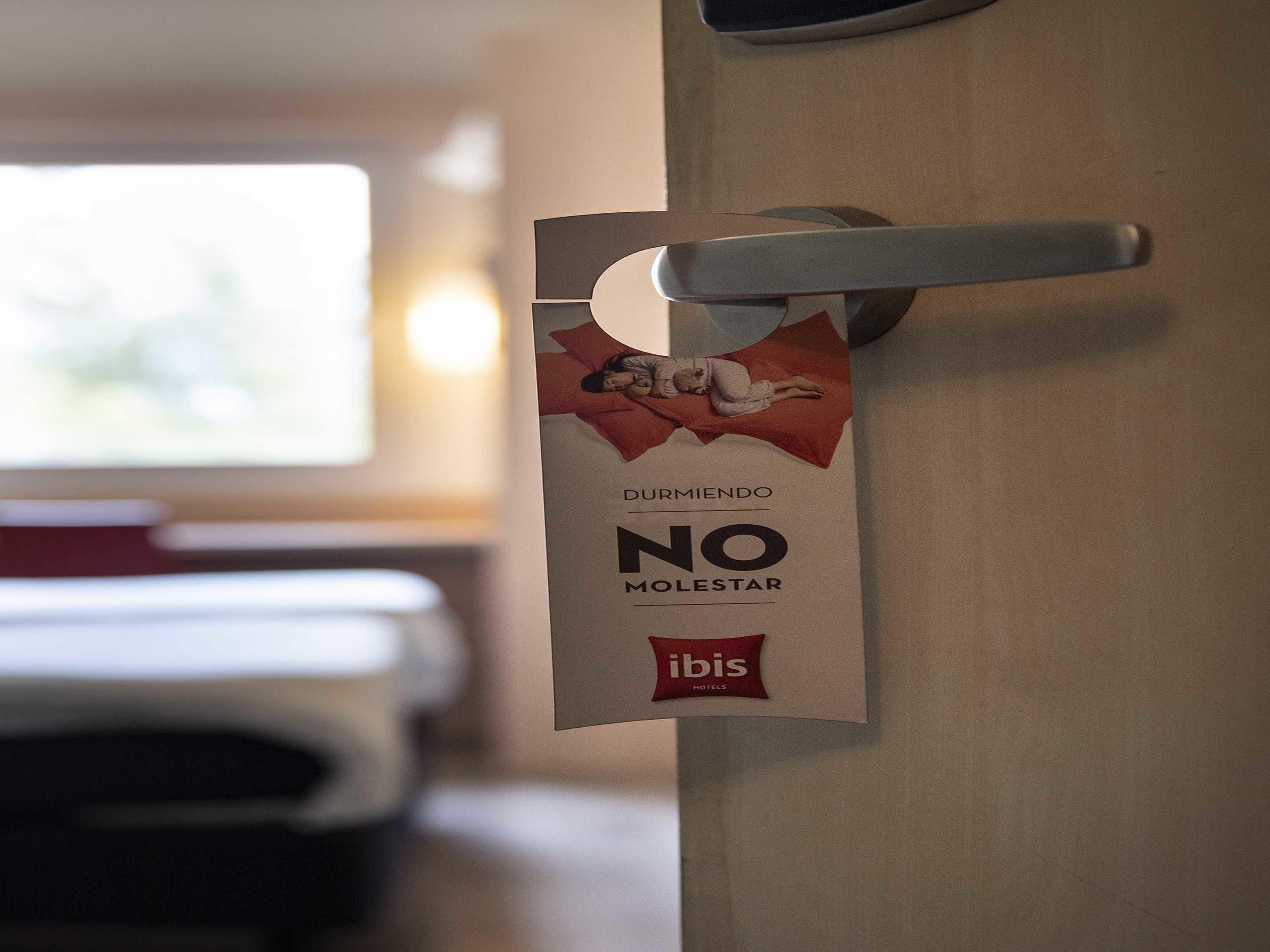 A door with a sign that reads 'DURMIENDO NO MOLESTAR' and the logo 'ibis HOTELS'.
