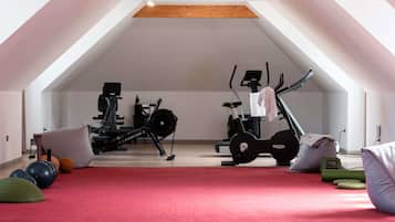 A spacious attic room with a sloped ceiling, exercise equipment, and a red carpet.