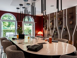 A modern conference room with a large oval table, multiple chairs, a laptop, and a potted plant. - Mercure Maintenon (Maintenon)