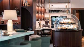 A modern bar area with a central display case, shelves with bottles, and a seating area with chairs.