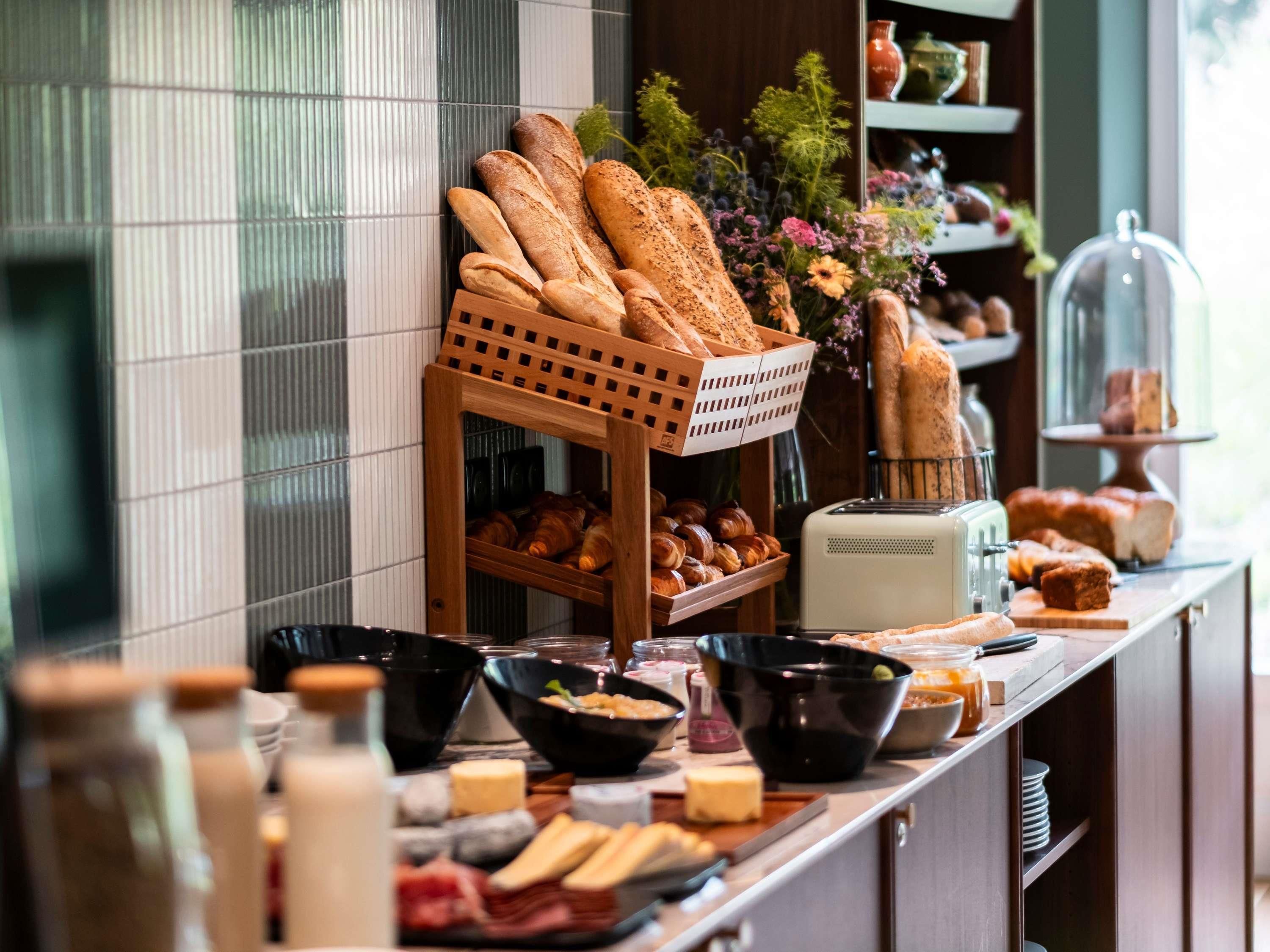 A breakfast buffet with various breads, pastries, and cheeses.