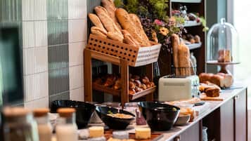 A breakfast buffet with various breads, pastries, and cheeses.