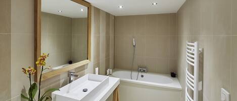 A modern bathroom with a white sink, mirror, and bathtub.