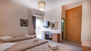 A hotel room with two beds, a desk, a television, and a wardrobe. - Hotel Taxiarhis (Pineios)