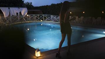 A swimming pool with a white fence and chairs around it.