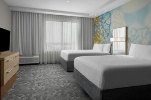 A hotel room with two beds, a TV, a dresser, and a large window with curtains. - Courtyard Houston Katy Mills (Katy)