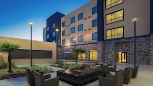 A hotel courtyard with outdoor seating, a water feature, and a stone wall. - Courtyard Houston Katy Mills (Katy)