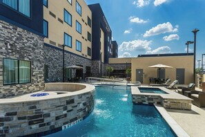A hotel with a swimming pool, stone walls, and outdoor seating areas. - Courtyard Houston Katy Mills (Katy)