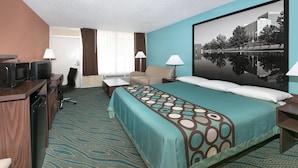 Una habitación de hotel con cama, escritorio, silla y un ventanal grande.