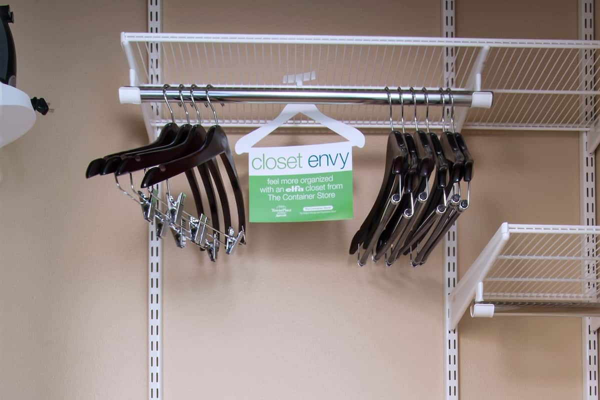 Storage area with shelving unit, scissors, hanging organizer, towel, and laundry basket.