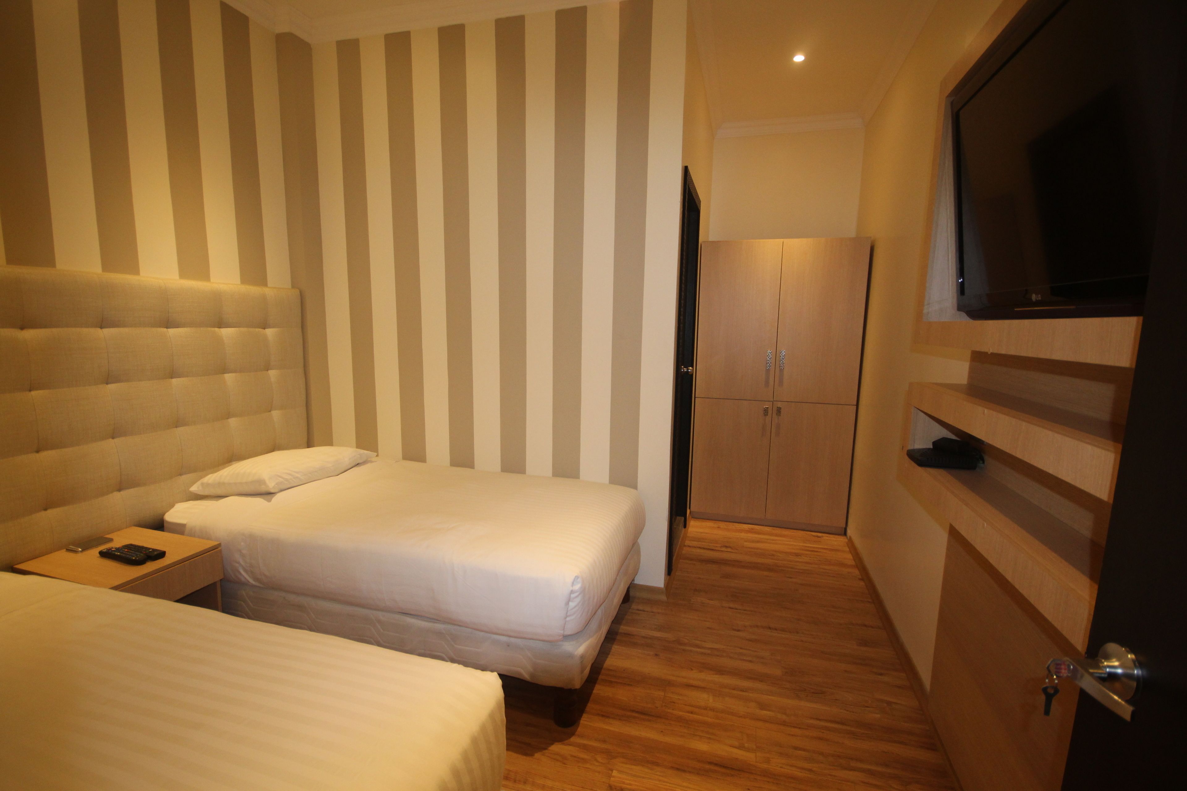 Ein Hotelzimmer mit zwei Betten, einem Kleiderschrank und einem Fernseher.