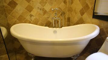 A white clawfoot bathtub in a bathroom with a tiled wall.