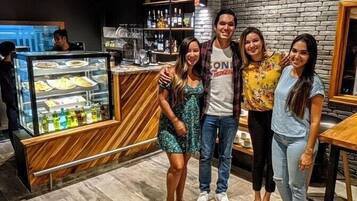 A group of people posing in a restaurant with a brick wall and a dessert display.