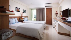 A hotel room with two beds, a desk with a laptop, a TV, and a window with curtains. - KC Place Srinakarin (Bangkok)