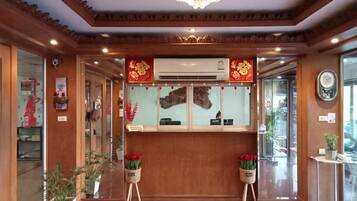 A reception area with a wooden reception desk, a chandelier, and potted plants.