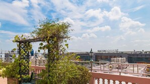 A rooftop terrace with a pergola, potted plants, a bench, and a view of the cityscape including a building labeled "SEACONSQUARE". - KC Place Srinakarin (Bangkok)