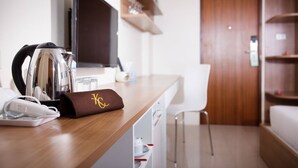 A hotel room with a wooden counter, a kettle, a phone, and a brown bag with a logo. - KC Place Srinakarin (Bangkok)
