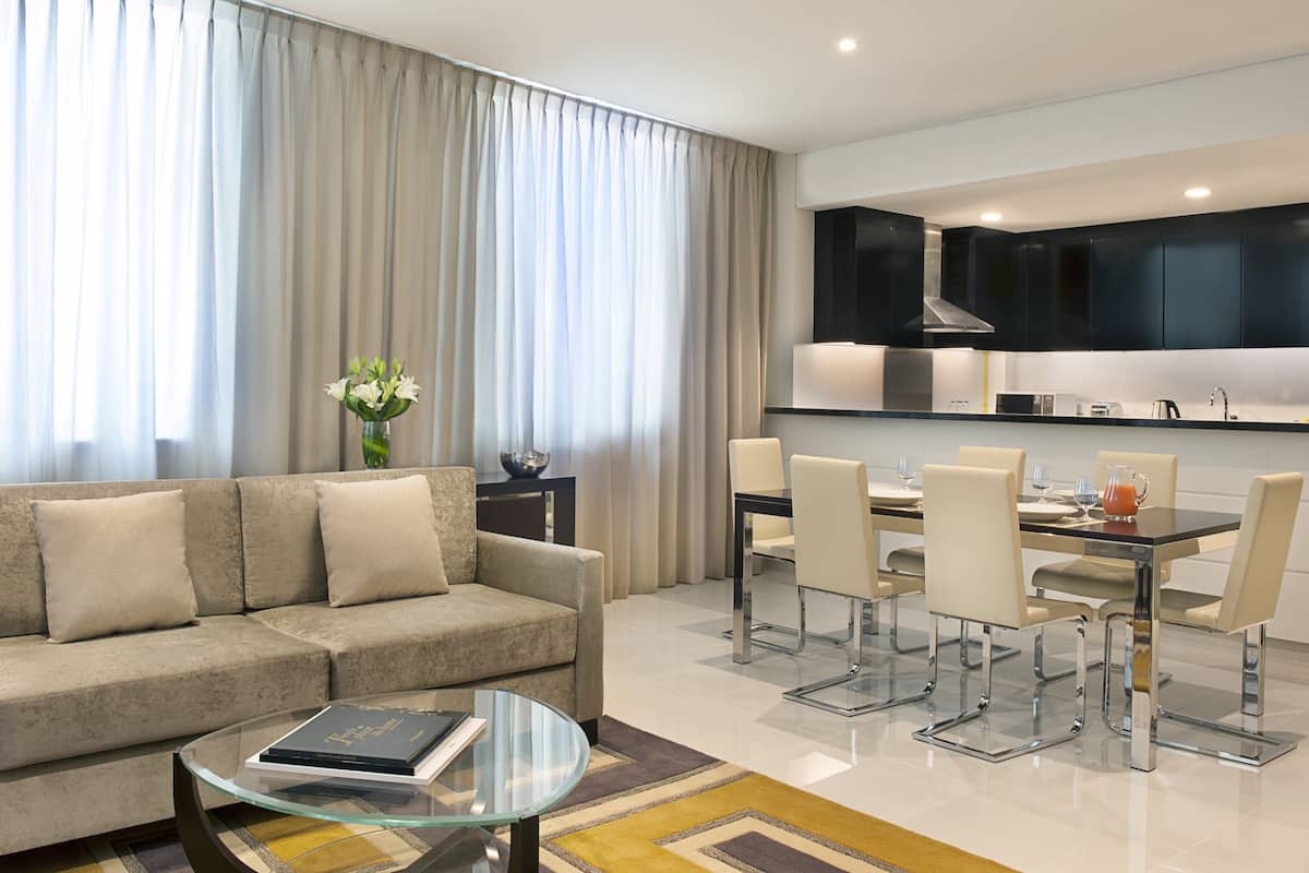 A modern living room with a sofa, coffee table, and dining area with chairs and a table.