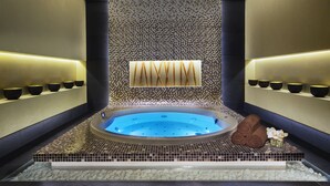 A spa area with a central hot tub, tiled walls, and shelves with bowls. - DAMAC Maison Cour Jardin (Dubai)