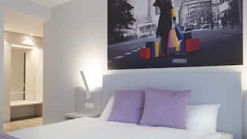 Een moderne hotelkamer met een groot bed, een nachtkastje en een aan de muur hangend schilderij van een stadsgezicht.