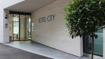 Un bâtiment moderne avec une enseigne indiquant « HÔTEL CITY » et un pot de fleurs au premier plan.