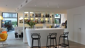 Uma área de bar moderna com ilha central, banquetas e uma variedade de garrafas nas prateleiras.