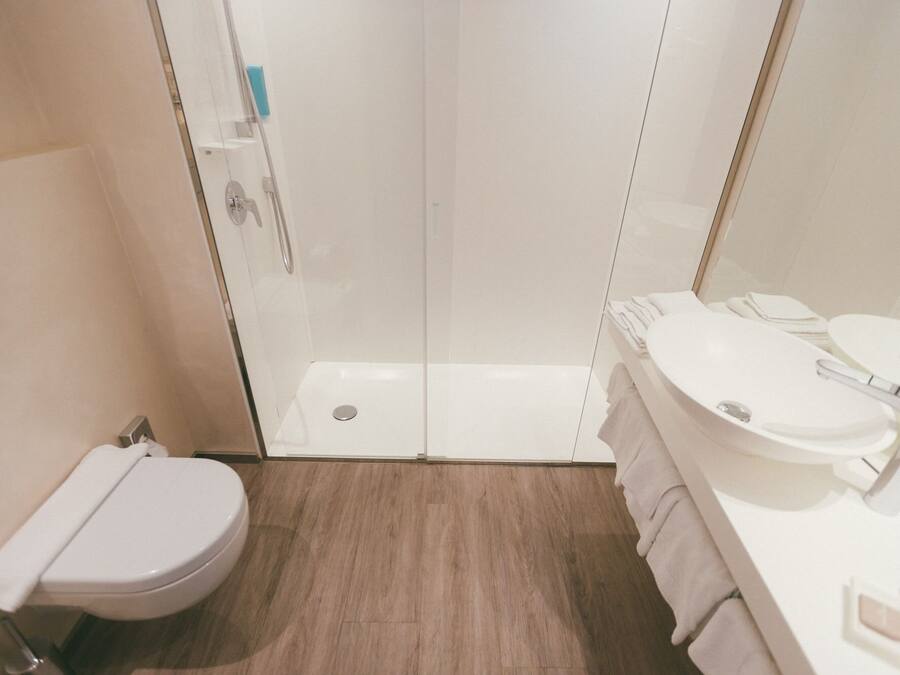 A modern bathroom with a glass-enclosed shower, a white toilet, and a sink with a mirror.
