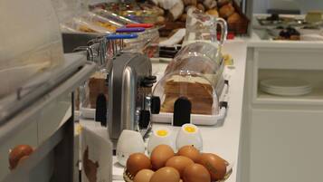 A buffet setup with various food items, including bread, pastries, and eggs.