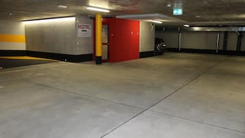 Ett parkeringsgarage med en hotellentrén, som markeras med en skylt och en röd dörr.